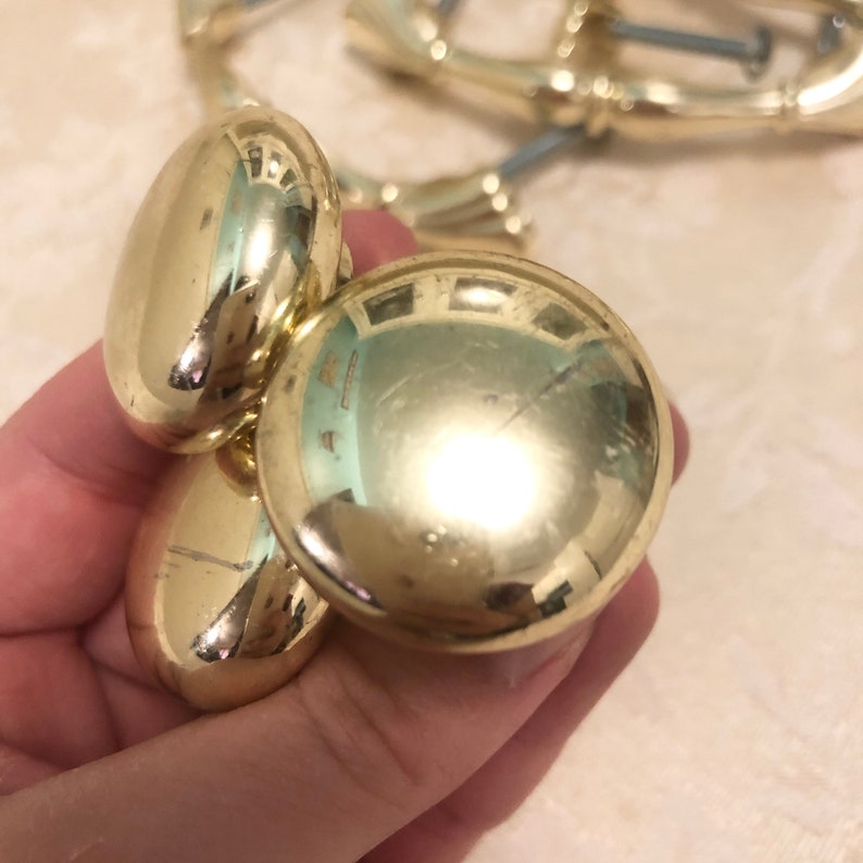 Puede incluir: Tres pomos de armario de color dorado con un dise&ntilde;o redondo y liso. Los pomos son de metal y tienen un acabado brillante.