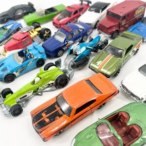 May include: A collection of toy cars in various colors, including red, green, blue, orange, and black. The cars are made of metal and plastic and have different styles, including sports cars, trucks, and race cars.