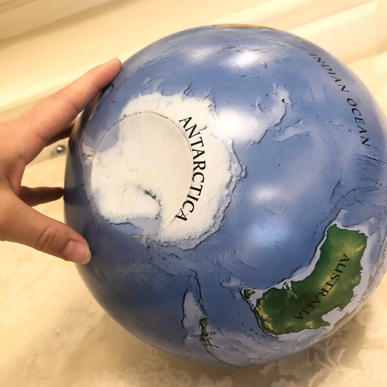 May include: A blue globe with a white outline of Antarctica and the text "ANTARCTICA" printed on it. The globe also shows Australia and the Indian Ocean.