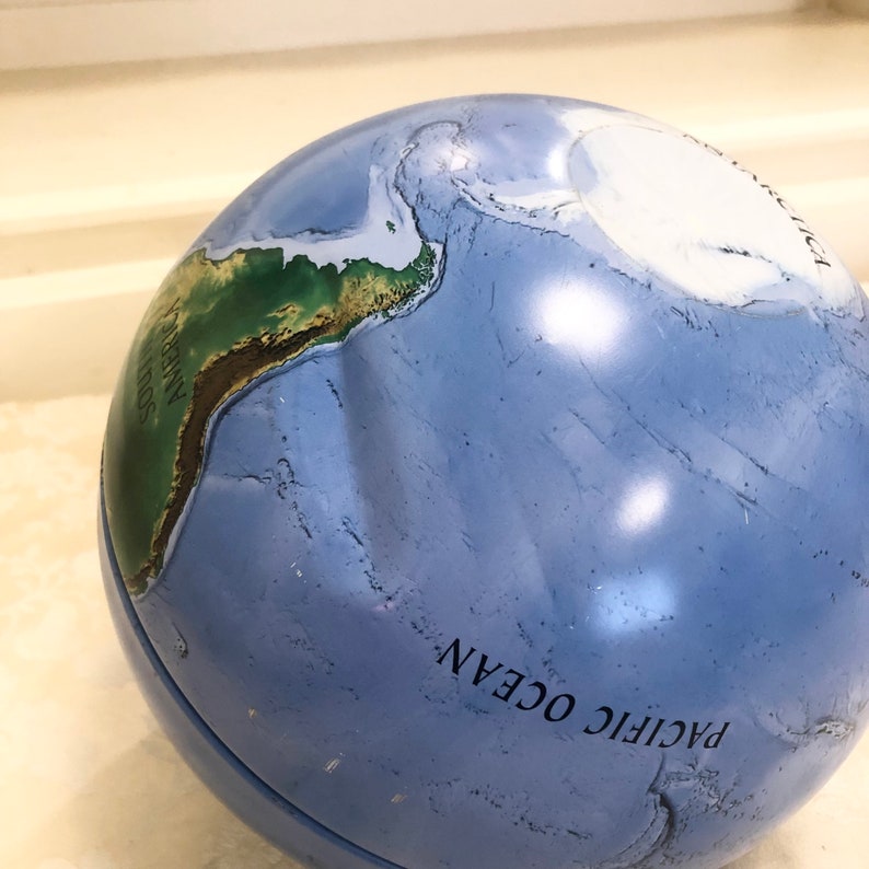 May include: A blue globe with a green and brown map of South America. The globe is labeled "PACIFIC OCEAN".