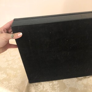 May include: Black rectangular box with a smooth, slightly textured surface. The box is closed and appears to be made of a sturdy material.