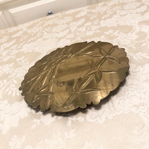 May include: A brass serving tray with an embossed design of bamboo stalks and leaves. The tray has a scalloped edge and is in good condition.