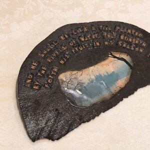 May include: A dark brown wooden plaque with a quote from the Bible, "And he shall be like a tree planted by the rivers of water, that bringeth forth his fruit in his season."