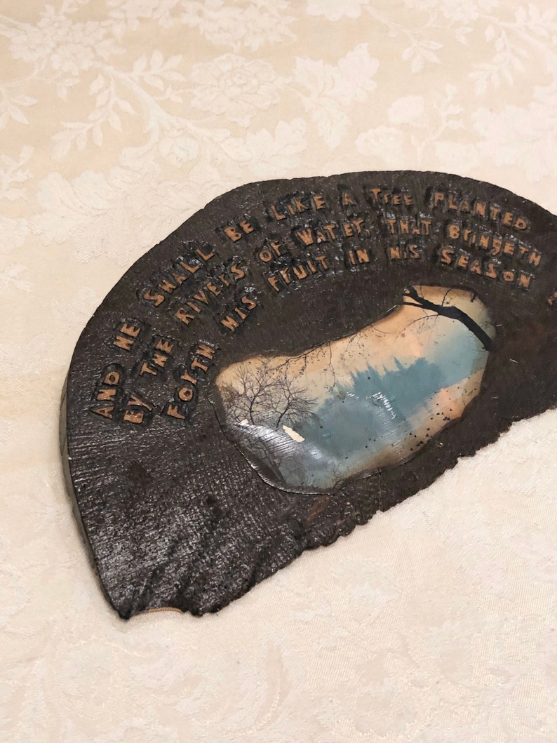 May include: A dark brown wooden plaque with a quote from the Bible, "And he shall be like a tree planted by the rivers of water, that bringeth forth his fruit in his season."