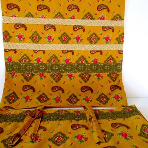 May include: A set of three yellow fabric panels with a paisley and floral pattern. The panels have a brown and white lace trim.