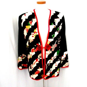 May include: A black and white patterned kimono with red trim and floral accents. The kimono has a long, open front and is made of a lightweight fabric.