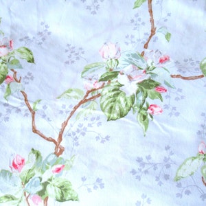 May include: A light blue fabric with a floral pattern of pink and white flowers and green leaves. The flowers are arranged in clusters along brown branches.
