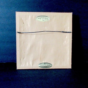 May include: The back of a framed print with a gold label that reads "The Commemorative Paper", and a smaller gold label that reads "The Commemorative Paper, Inc."