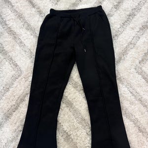 Może przedstawiać: Czarne spodnie z rozszerzanymi nogawkami, ze sznurkiem w pasie i pionowymi szwami. Spodnie mają luźny krój i lekkie rozszerzenie u dołu. Materiał wydaje się być miękki i wygodny.