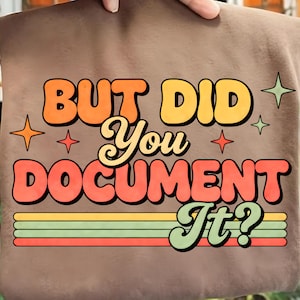 May include: A brown sweatshirt with the text "BUT DID YOU DOCUMENT IT?" in retro-style orange, yellow, and red lettering. The design includes star and stripe accents, creating a vintage aesthetic.