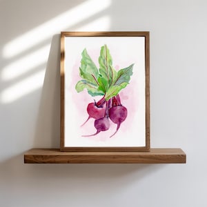 May include: A framed watercolor painting depicting three vibrant purple beets with long, lush green leaves featuring prominent red veins, set against a soft, pale pink wash background within a simple wooden frame.