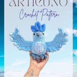 May include: A light blue crochet bird with outstretched wings, featuring a darker blue crest and feet. The text "ARTICUNO Crochet Pattern" is displayed above the bird, with the handle "@hookedByBoo" below. The bird is held against a sky background.