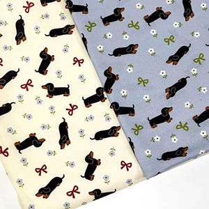 Könnte beinhalten: Zwei Stoffmuster mit einem sich wiederholenden Muster aus schwarzen Dackel-Hunden, roten Schleifen und kleinen weißen Blumen. Ein Stoff ist cremefarben, der andere hellblau. Die Dackel sind in verschiedenen Posen.