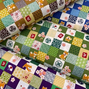 Può includere: Primo piano di diversi rotoli di tessuto fantasia. Il tessuto presenta un design patchwork con quadrati di vari motivi, tra cui cani Shiba Inu, fiori di ciliegio e forme geometriche nelle tonalità del verde, giallo, marrone, blu e viola.