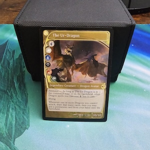 Puede incluir: Una carta de Magic: The Gathering con "The Ur-Dragon", una Criatura Legendaria Avatar Dragón. La carta tiene un borde dorado con una ilustración detallada de un dragón. La fuerza y resistencia de la carta son 10/10.