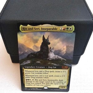 Pode incluir: Uma carta colecionável Magic: The Gathering intitulada Rin and Seri, Inseparable, apresentando um cão preto e um gato branco em uma paisagem montanhosa. O texto da carta detalha habilidades para criar fichas e causar dano baseado nas unidades.