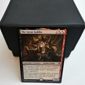 May include: A Magic: The Gathering trading card titled The Great Goblin, featuring a legendary creature illustration. The card displays a red and black border, text detailing its abilities, a 3/2 power and toughness, and the set symbol at the bottom.