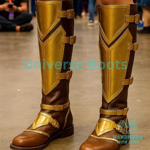 May include: Brown and gold knee-high boots with decorative gold panels and buckles. The boots have a brown base with gold accents and are designed with multiple straps and buckles. The text "Universe Boots" is visible on the boots.