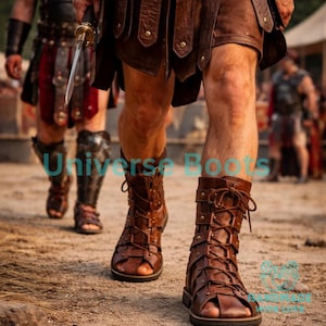Op de afbeelding: Bruine leren gladiatorsandalen met vetersluiting. De sandalen worden gedragen met een bruine leren rok en harnas. De afbeelding toont een historisch of fantasiethema, met andere figuren in vergelijkbare kleding op de achtergrond.