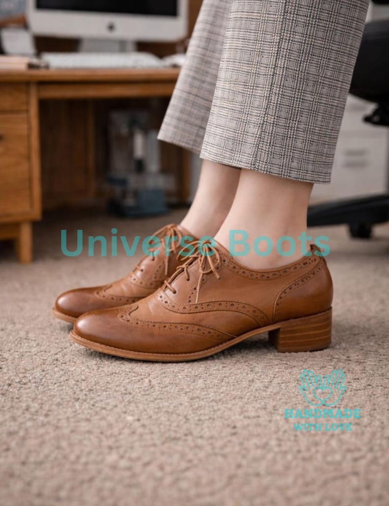 May include: Brown leather brogue shoes with a low block heel. The shoes have decorative perforations and lace-up closures. The text "Universe Boots" is visible in the image.