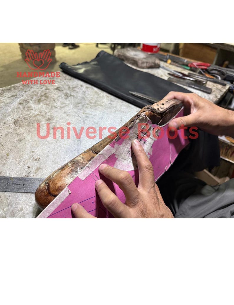 Op de afbeelding: Een houten schoenleest met een roze papieren patroon. De tekst "HANDMADE WITH LOVE" en "Universal Boots" zijn zichtbaar. De afbeelding toont het proces van schoenmaken.