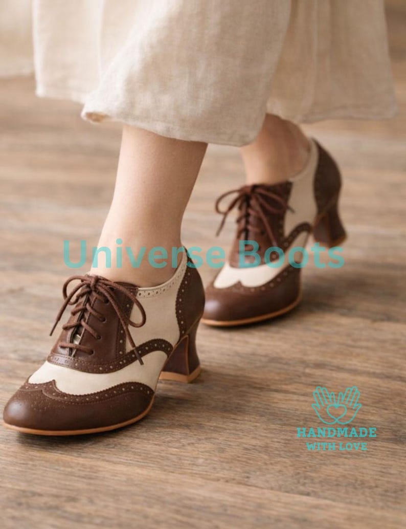 May include: Brown and cream-colored Oxford-style shoes with a lace-up design. The shoes have a wingtip design and a stacked heel. The shoes are made of leather and have a classic, vintage look. The shoes are a size 8.