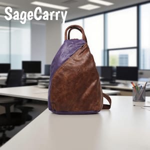 Puede incluir: Mochila de dos tonos con la parte superior morada y la inferior marrón. La bolsa tiene un asa superior y una sola correa para el hombro. El texto "SageCarry" está en la esquina superior izquierda. La bolsa está sobre un escritorio blanco en un entorno de oficina.