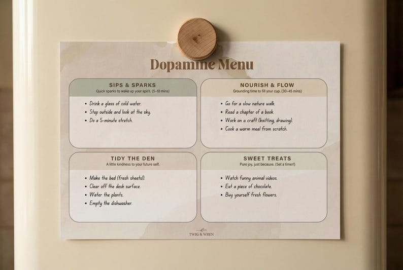 May include: A printed "Dopamine Menu" on a refrigerator door, held by a wooden magnet. The menu features four sections with self-care suggestions, including "Sips & Sparks" and "Sweet Treats".