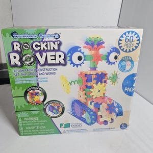 May include: A Techno Gear Rockin' Rover construction set box. The box is green, white, and blue, with images of a robot made of colorful gears. The set includes 60+ pieces and is recommended for ages 6 and up.