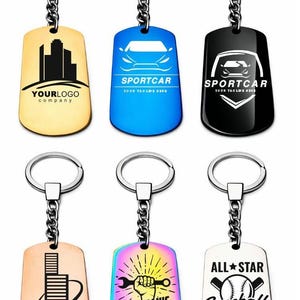 May include: Six metal dog tag keychains with silver split rings and chains. The tags feature various designs: a gold city skyline, a blue car with 'SPORTCAR', a black car emblem, a copper building, a rainbow wrench graphic, and a baseball logo.