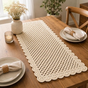 May include: A rectangular cream-colored crochet table runner featuring a repeating open-work grid pattern and a decorative scalloped edge. The runner is crafted from yarn and lies flat, showcasing a consistent texture and intricate stitch detail.