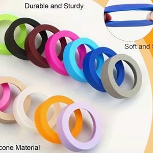 May include: A collection of colorful silicone rings in various shades, including green, black, burgundy, pink, blue, and gray. The image also shows a close-up of a blue ring being stretched, with the text "Soft and Stretchy". The text "Durable and Sturdy" is also visible.