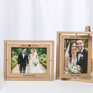 Może przedstawiać: Dwie drewniane ramki na zdjęcia ze zdjęciami ślubnymi. Jedna ramka ma napis "Ethan ❤ Olivia" i "5.11.2025". Druga ramka ma napis "Save The Date" i "05.11.2025". Ramki znajdują się na białej powierzchni.