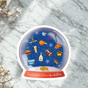 May include: A snow globe sticker featuring a blue background with white snowflakes and various icons including a hockey stick, ice skate, football, pizza slice, chicken wing, beer, and the text There's snow place like buffalo on the red base.