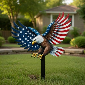 Puede incluir: Una estaca de jardín de metal con un águila calva detallada con las alas extendidas. Las alas están pintadas con el diseño de la bandera estadounidense, incluyendo azul con estrellas blancas y rayas rojas y blancas. El águila tiene una cabeza blanca, cuerpo marrón y garras amarillas.