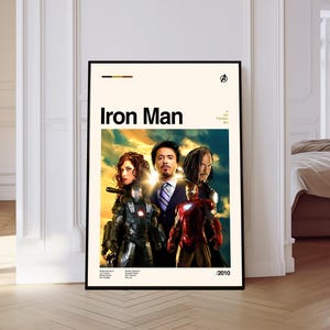 May include: A framed poster featuring the movie "Iron Man" with the title in bold black letters. The poster showcases several characters from the film, including Iron Man in his red and gold suit. The background has a sunset-like sky.