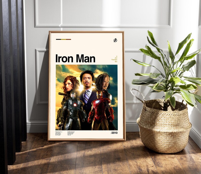 May include: Framed movie poster for "Iron Man" featuring the film's title in bold black letters. The poster showcases the main characters in costume against a vibrant, colorful background. The year 2010 is printed in the bottom right corner.