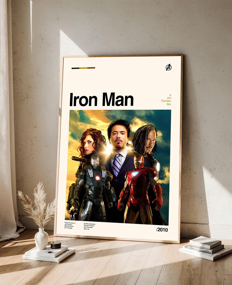 May include: A framed movie poster for "Iron Man" featuring the film's title in bold black letters. The poster showcases images of the main characters, including Iron Man in his red and gold suit, and other actors. The poster is set against a cream background.