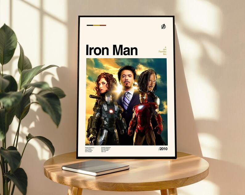 May include: Framed poster featuring the movie "Iron Man" with actors Robert Downey Jr., Gwyneth Paltrow, and Don Cheadle. The poster has a cream-colored background with the title "Iron Man" in bold black letters. The year 2010 is printed at the bottom.