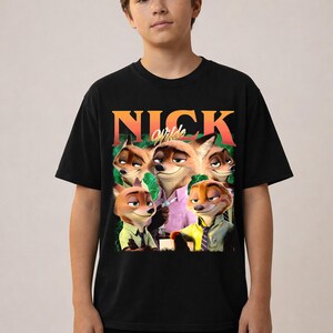 May include: Black t-shirt featuring a graphic of Nick Wilde from Zootopia. The design includes the name "NICK" in orange and the character's image. The shirt is worn by a person.