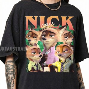 May include: Black t-shirt featuring a graphic of the character Nick Wilde from the animated film Zootopia. The design includes the name "Nick Wilde" in an orange and green font, with multiple images of the character.