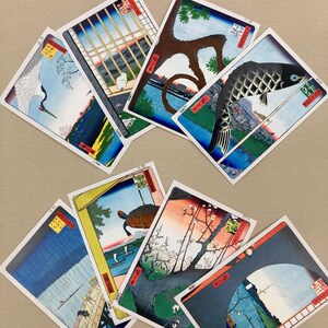 以下が含まれることがあります： 様々な風景を描いた日本の版画のコレクション。各プリントは、鶴、魚、橋など、自然の鮮やかな色と詳細なイラストを展示しています。プリントは長方形で、白い縁があります。