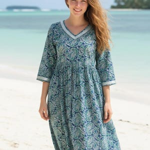 Knee-length blue and green paisley print dress with a V-neckline, three-quarter sleeves, gathered waist, and flowy flared skirt in lightweight fabric.