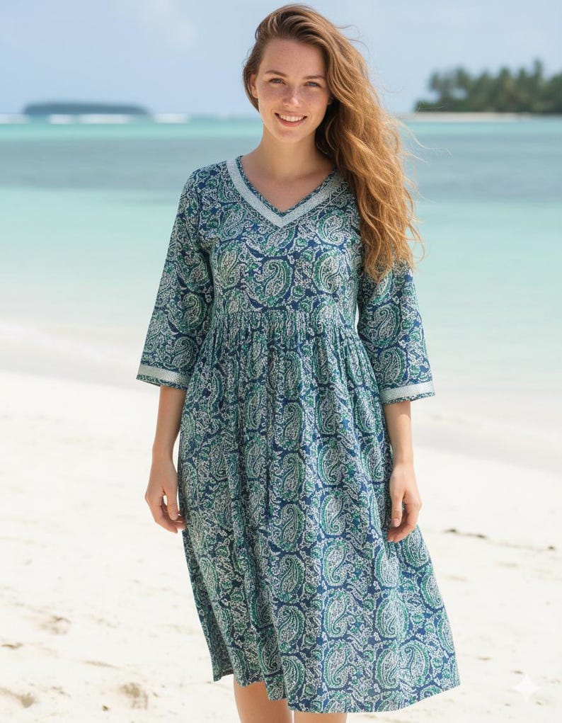 Knee-length blue and green paisley print dress with a V-neckline, three-quarter sleeves, gathered waist, and flowy flared skirt in lightweight fabric.