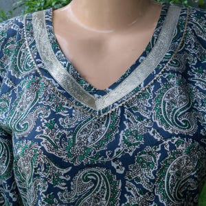 Puede incluir: Top con cuello en V con estampado de cachemira en azul marino, blanco y verde. El escote est&aacute; adornado con una cinta plateada. La tela tiene un aspecto suave y fluido.