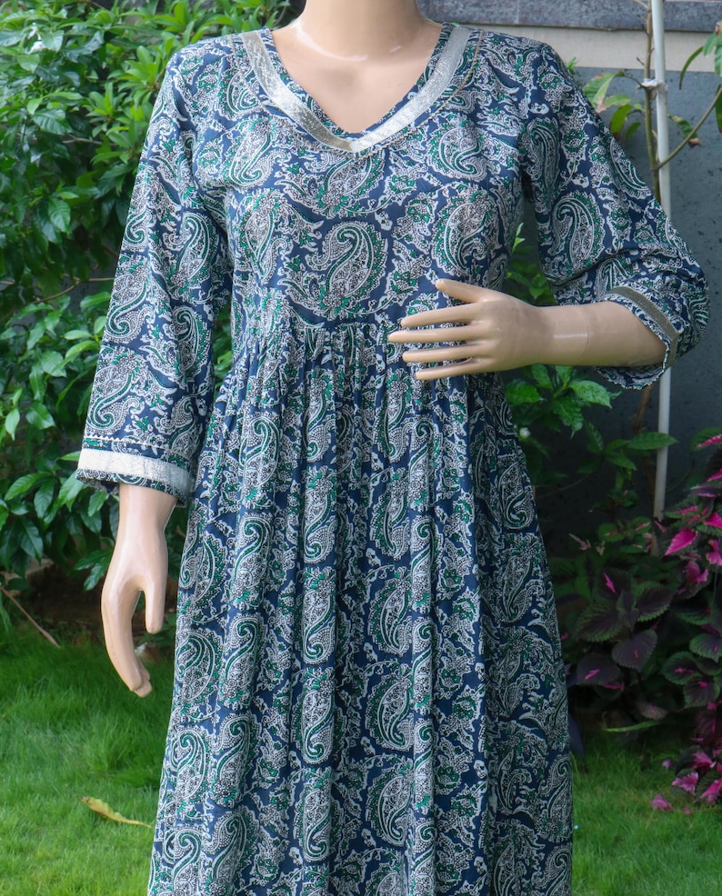 Puede incluir: Vestido largo y fluido con estampado de cachemir en azul marino, verde y blanco. El vestido presenta un escote en V y mangas largas con ribete blanco. La tela parece ligera, ideal para climas c&aacute;lidos. Mide aproximadamente 140 cm.