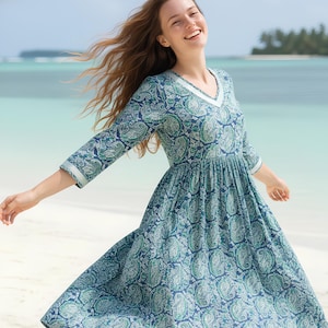 Knee-length blue and green paisley print dress with a V-neckline, three-quarter sleeves, gathered waist, and flowy flared skirt in lightweight fabric.