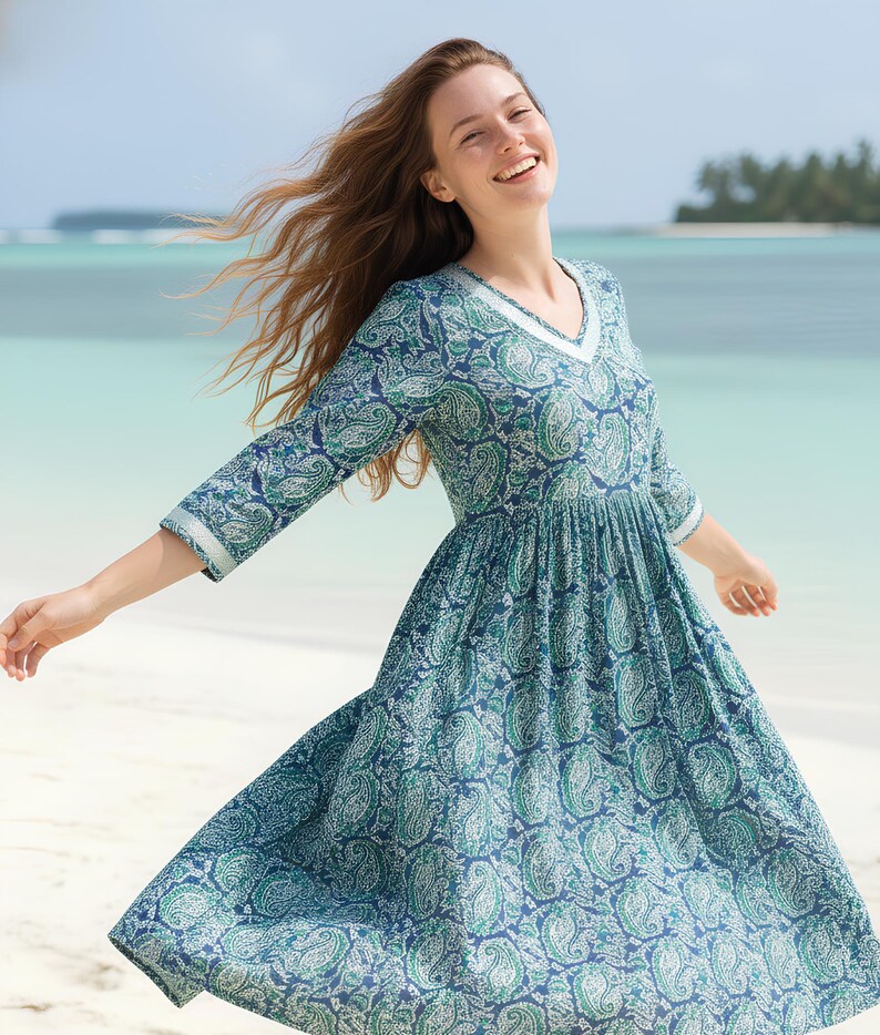 Knee-length blue and green paisley print dress with a V-neckline, three-quarter sleeves, gathered waist, and flowy flared skirt in lightweight fabric.