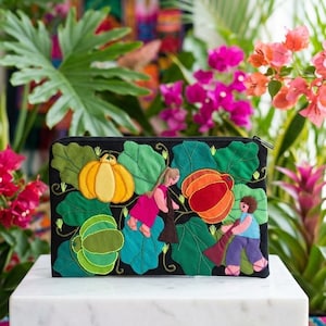 Peut inclure: Pochette noire zippée avec broderie de citrouilles et personnages colorés. Le motif présente des citrouilles jaunes, oranges et vertes avec des personnages en vêtements roses et bleus, sur de grandes feuilles vertes.