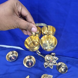 May include: A set of polished brass kitchenware items including a four-compartment bowl unit with a central handle, two individual small bowls, a multi-petaled oil lamp, a lidded container, a decorative spoon, and a small handled ladle.